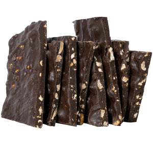 Close up of several pieces of bark candy stacked to expose the pistachios inside the dark chocolate. 