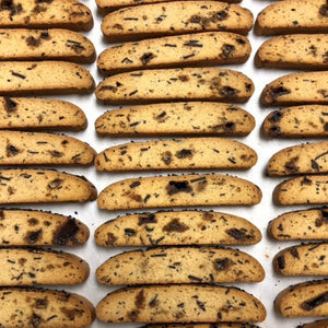 Sesame brittle biscotti laid out on a sheet pan exposing side-view of toffee inside the biscotti. 