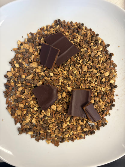 Gingerbread spices (ginger, cloves, cloves) on a white plate with 5 pieces of toffee brittle on top of the spices. 