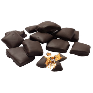 A pile of chocolate covered honeycomb candy pieces with one piece broken open to expose honeycomb candy inside.