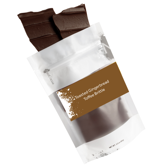 Brittle pieces spilling out of 3oz sized bag with brown label stating “Toasted Gingerbread Toffee Brittle” and NeoCocoa logo. On a white background. 