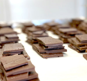 Stacks of broken smoky mocha brittle on a sheet pan showing thin layers of toffee and chocolate