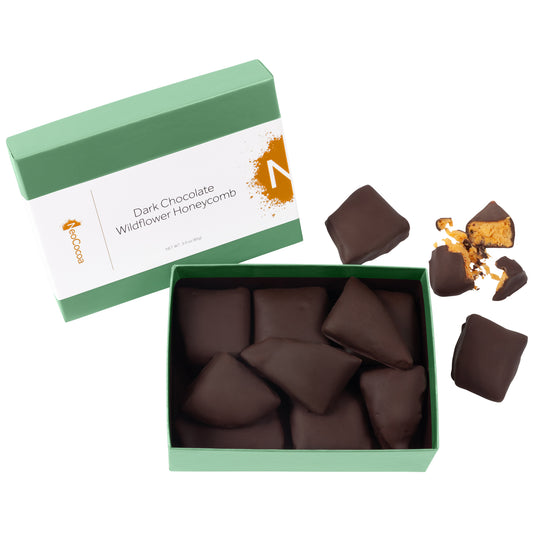 2 dimensional angle of opened 3oz green box with title of "Dark Chocolate Wildflower Honeycomb" with golden colored NeoCocoa logo and 3oz pile of chocolate covered honeycomb candy pieces inside the box bottom. One piece of candy broken open to expose honeycomb candy inside.