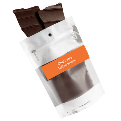 Chai Latte brittle pouring out of 3oz sized bag with label stating “Chai Latte Toffee Brittle” and NeoCocoa logo.