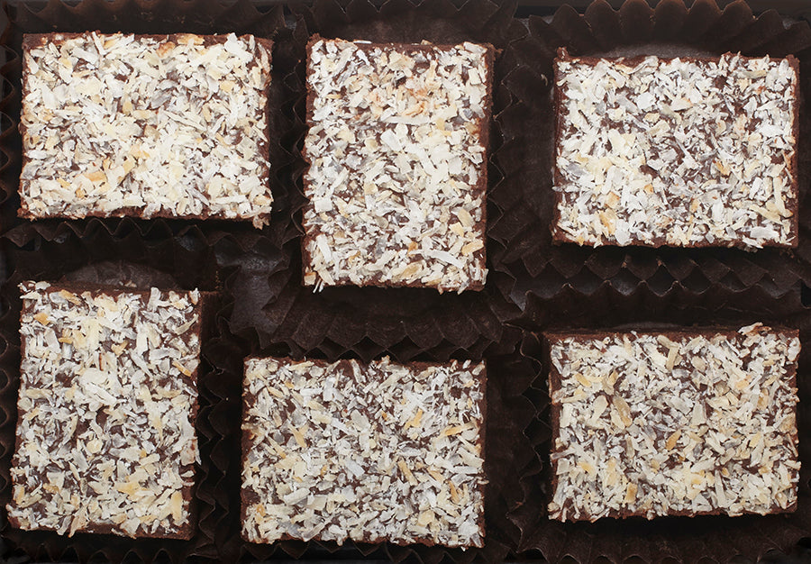View from above of the opened “Toasted Coconut” with six rectangle-shaped chocolate truffles arranged in two rows, 3 truffles per row, each in paper candy cup. 