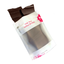 Load image into Gallery viewer, Milk Tea brittle pouring out of 3oz sized bag with label stating “Milk Tea Toffee Brittle” and NeoCocoa logo.